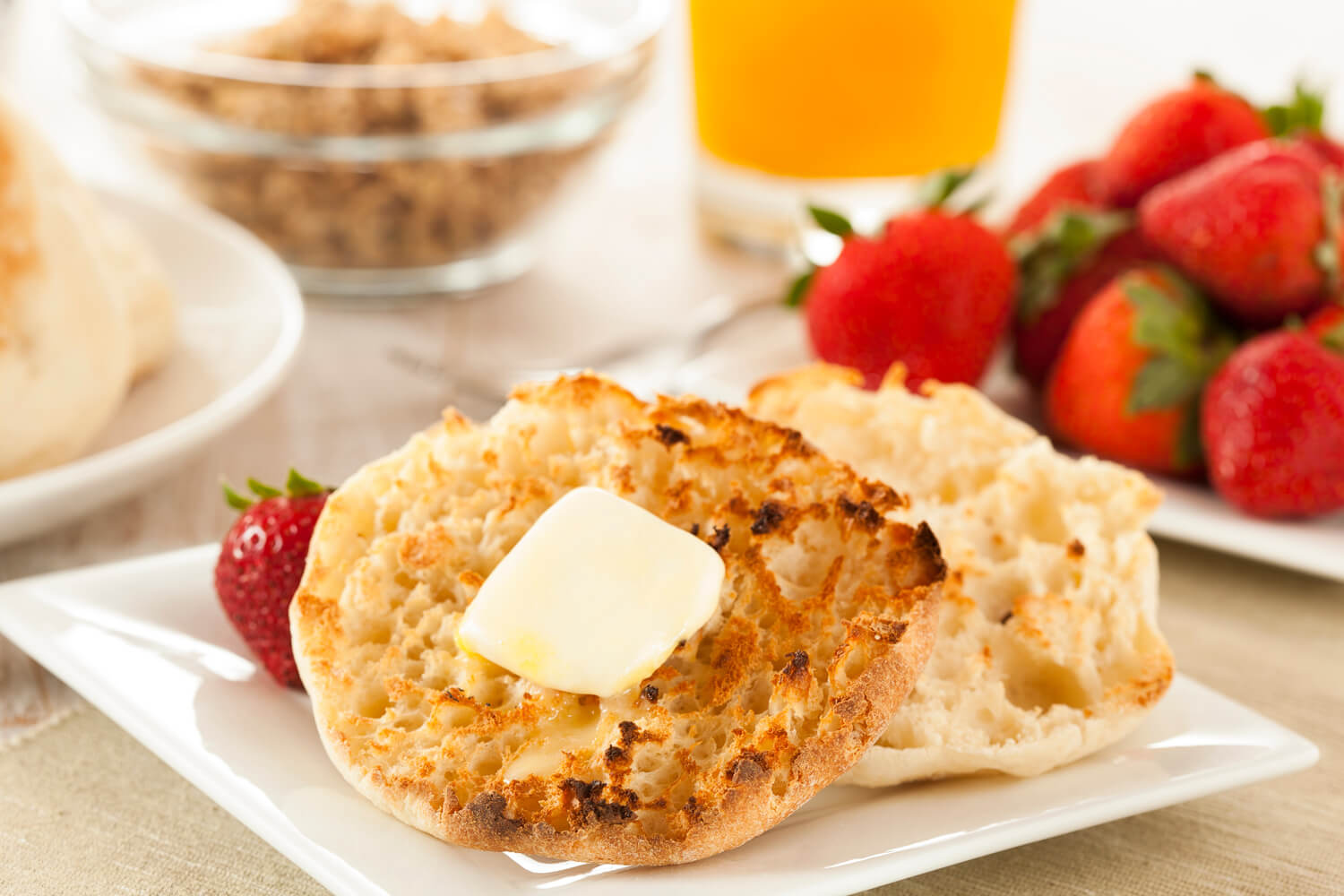 buttery english muffin with strawberries and orange juice